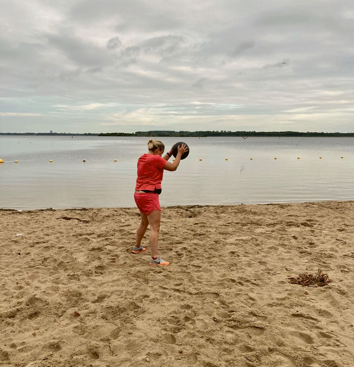 Training met een kettlebell op het strand aan een meer